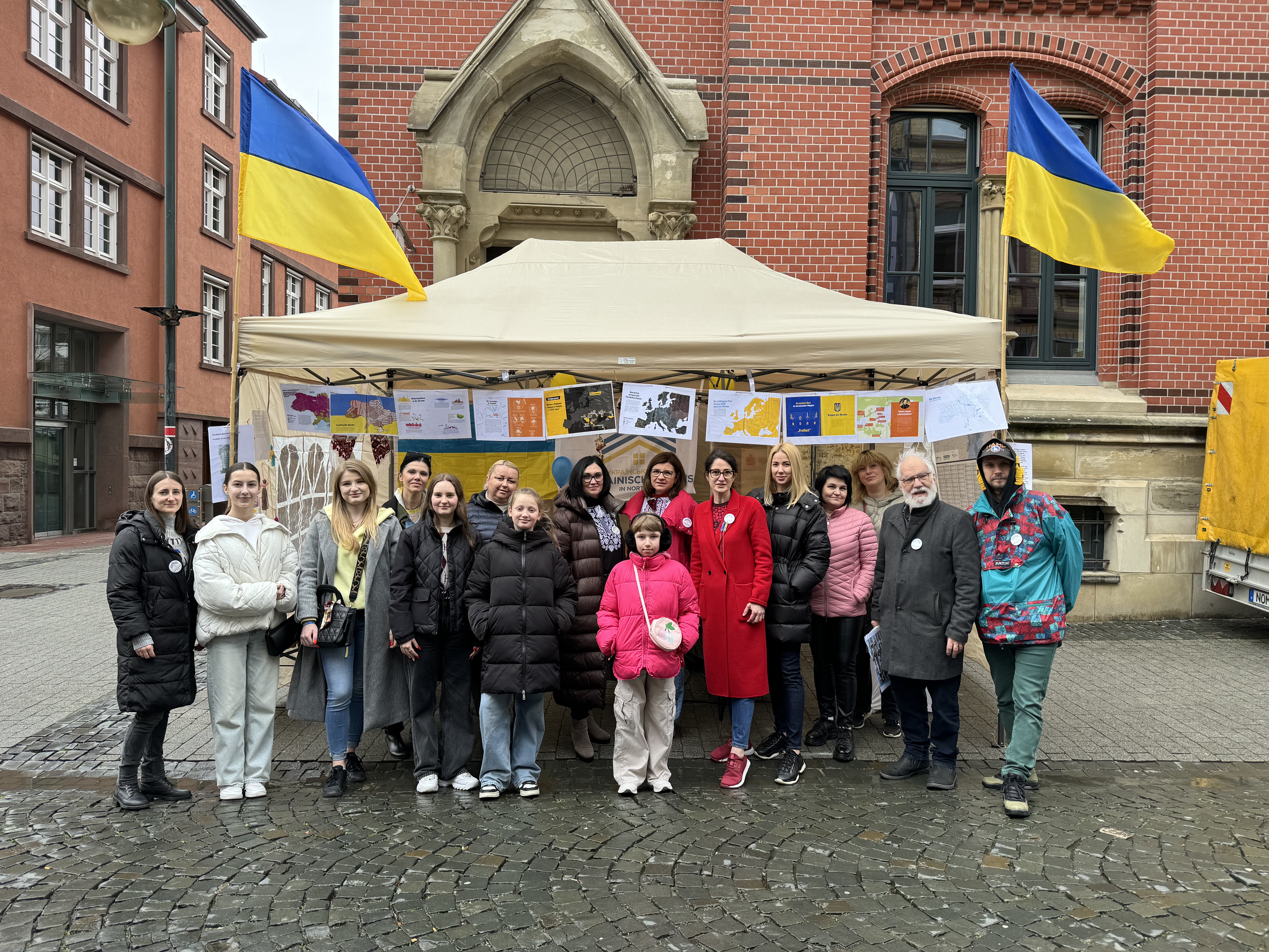  Ein Gruppenfoto vor einem weißen Stoffzelt mit Ukraineflaggen und Infotexten und dem Logo des Ukrainischen Haus Northeim.